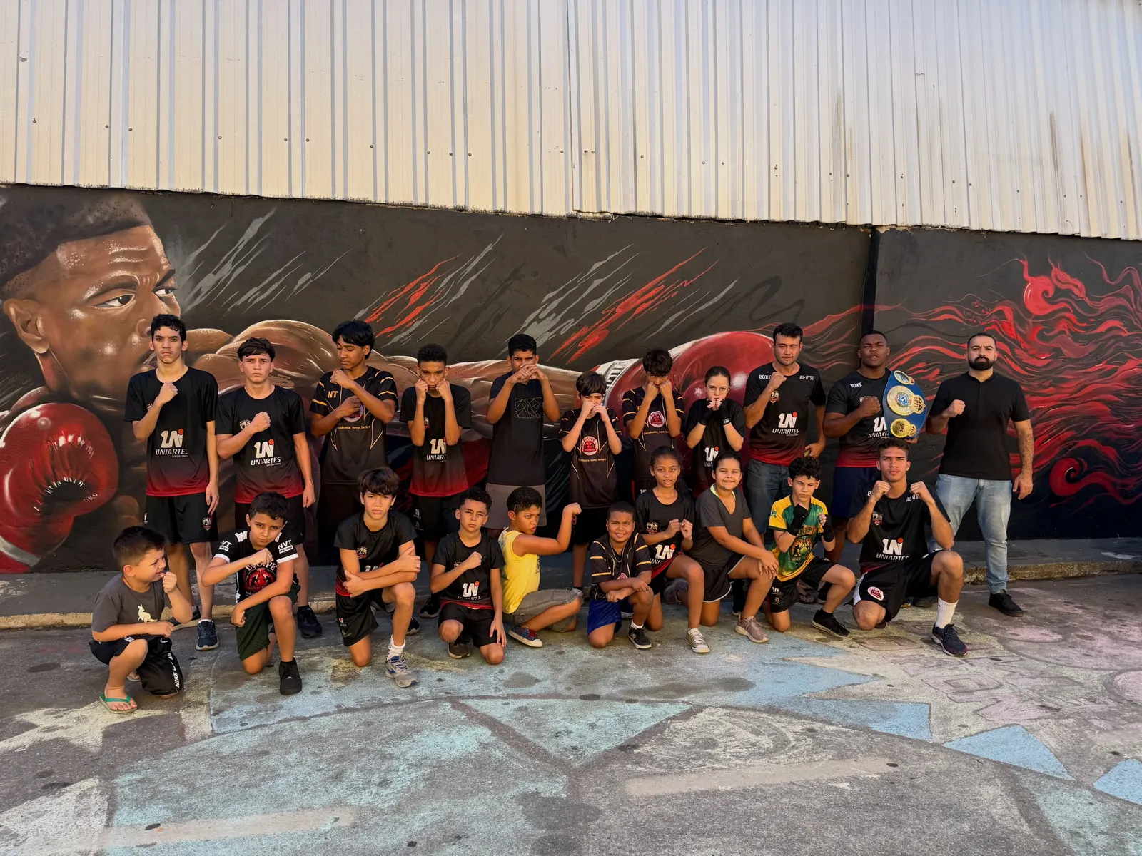 Turma de boxe do sábado posando diante de um mural grafitado
