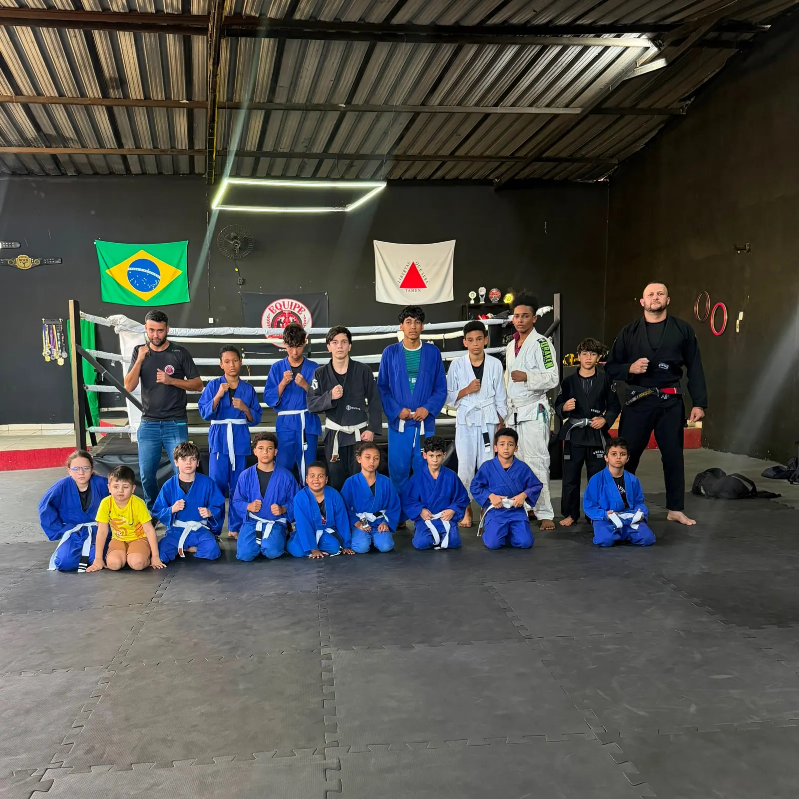 Crianças de quimono azul na turma de jiu-jitsu do Projeto Novo Tempo, com os professores